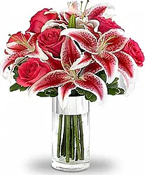 Rosas rojas , Lirios y flores variadas de temporada en colores cálidos con elegante composición a juego.